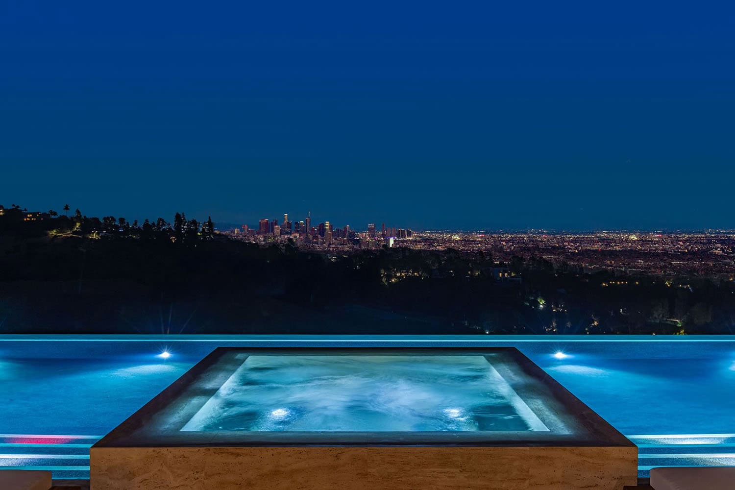 hillside home patio with a pool and a view over Beverly Hills at dusk