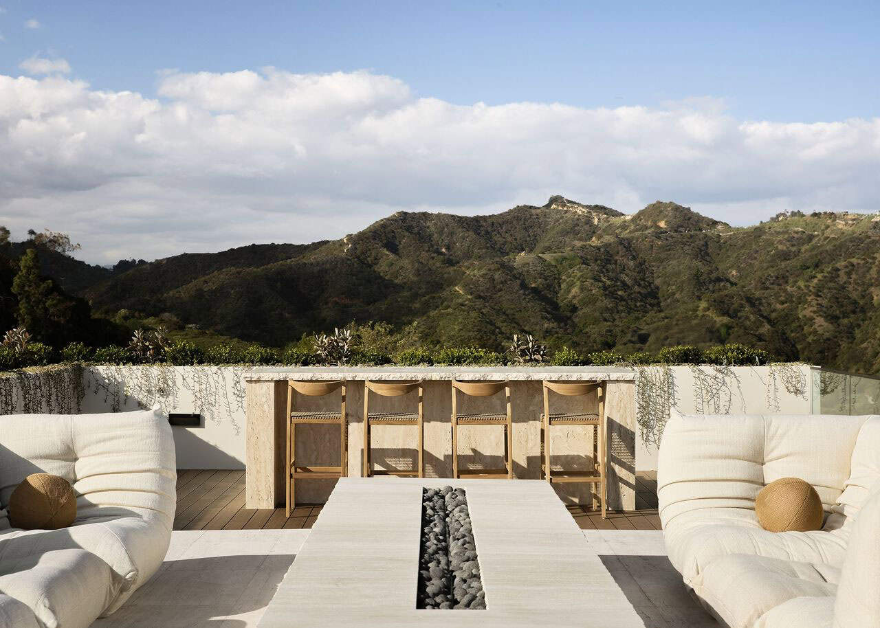 hillside home outdoor patio with a bar and seating around a fire pit