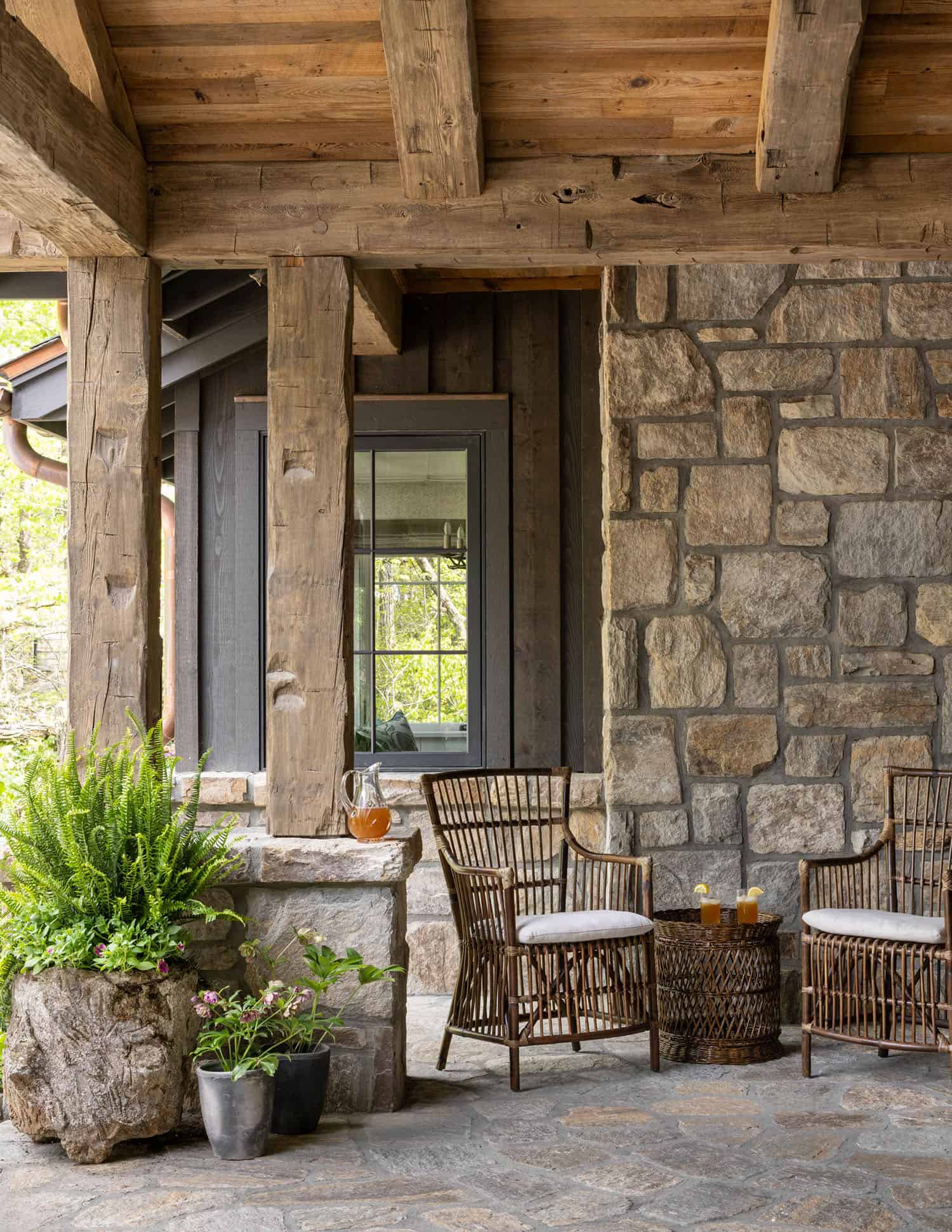 European-inspired covered porch with stone walls and outdoor furniture