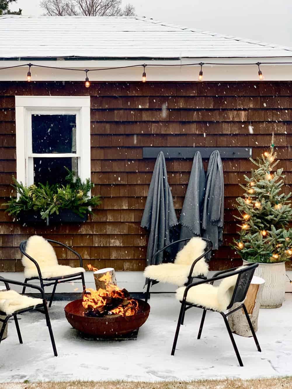 small backyard patio with modern chairs, wood stump side tables, and a fire pit in the winter