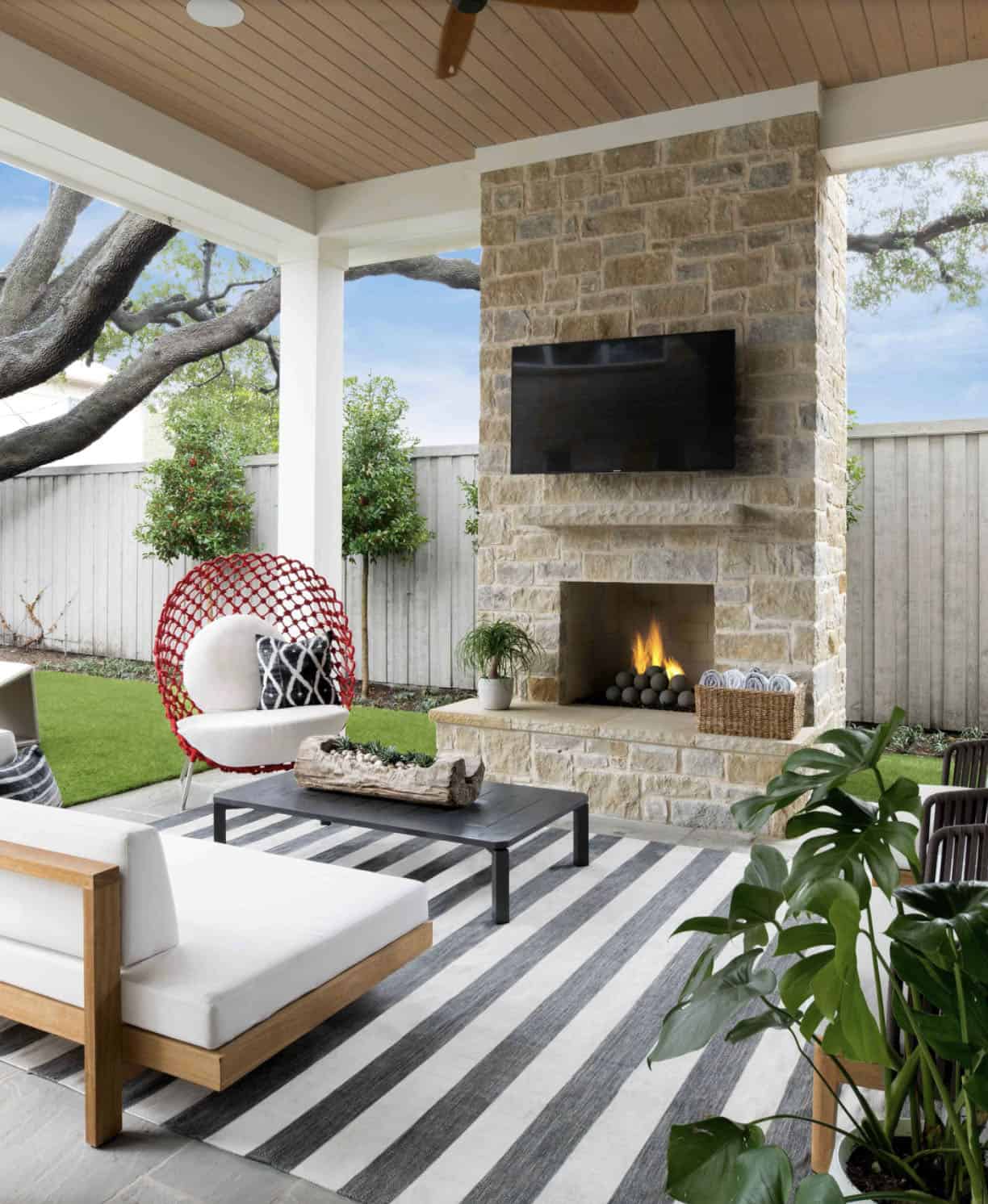 beach style covered patio with a fireplace and striped outdoor rug