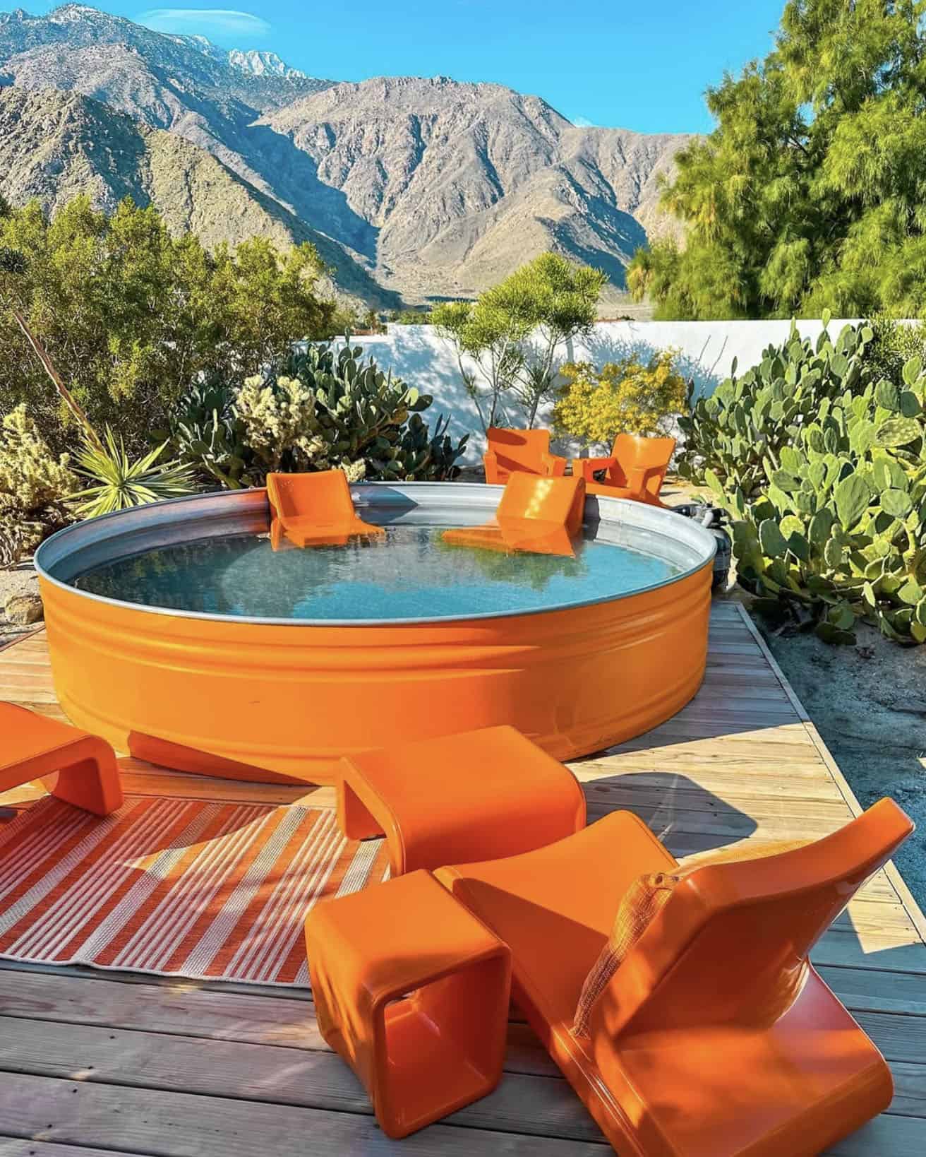 backyard patio with an orange stock tank pool and orange lounge chairs