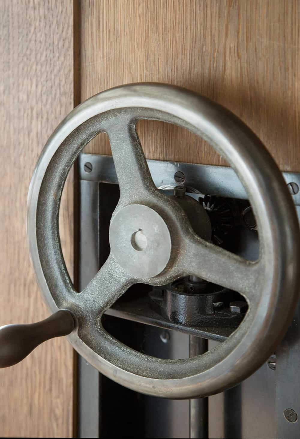 farmhouse style dining room with a rolling bookcase wall and hand crank wheel