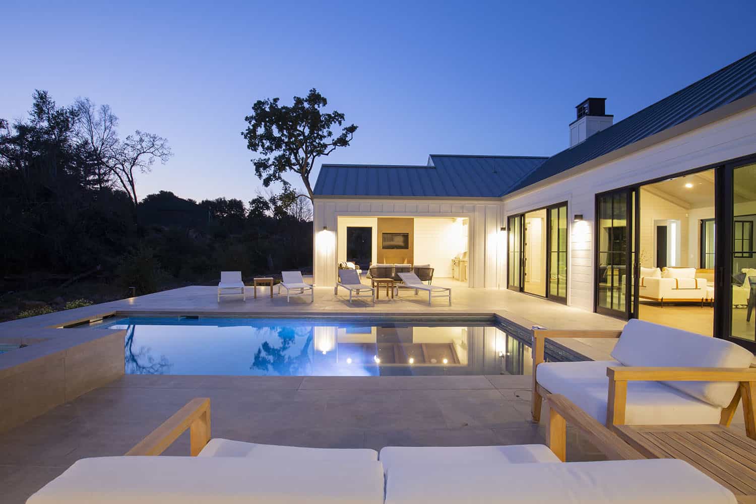 modern farmhouse style home exterior with a pool at dusk