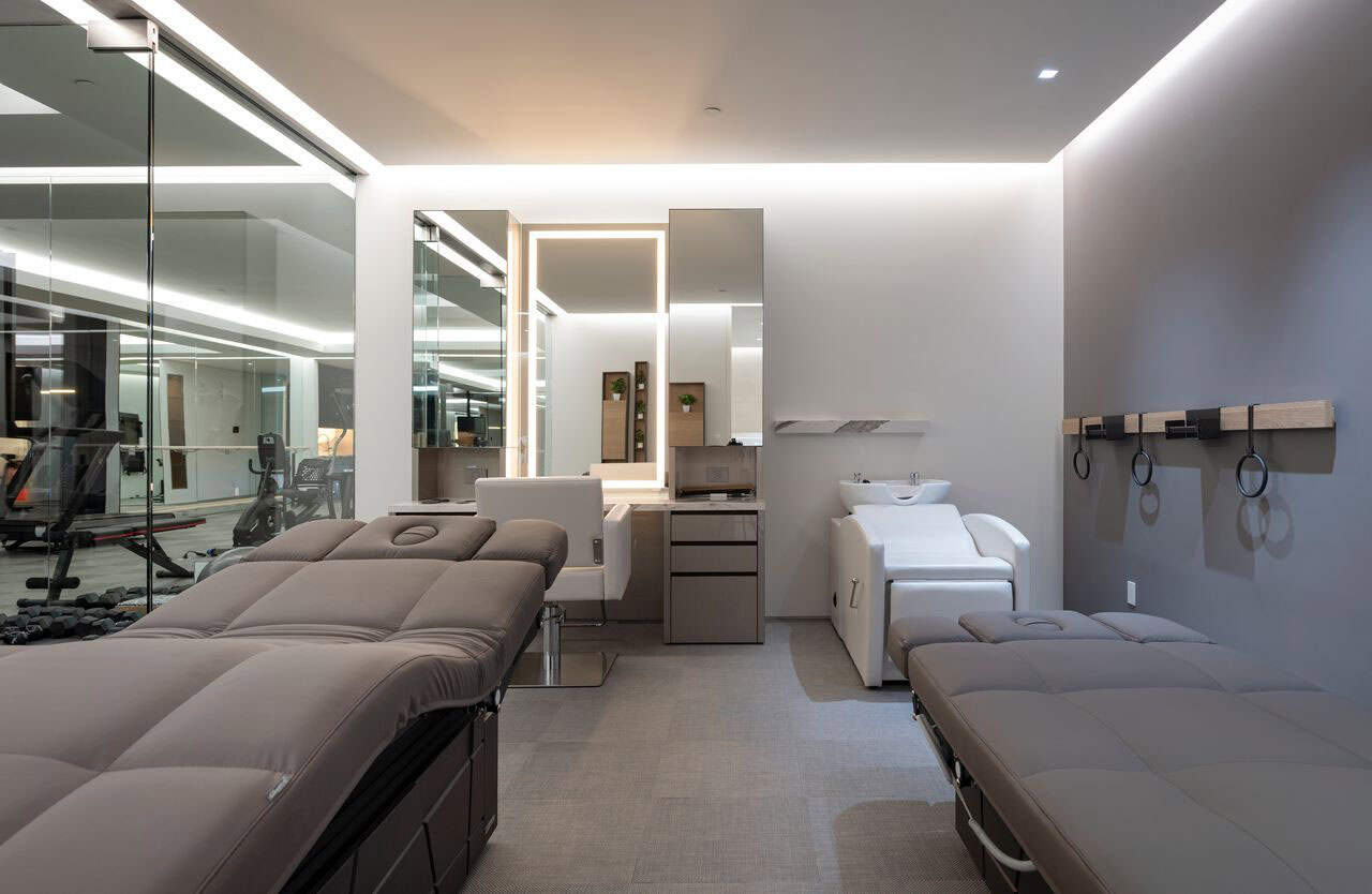 A room with massage tables and a barber station with a mirror 