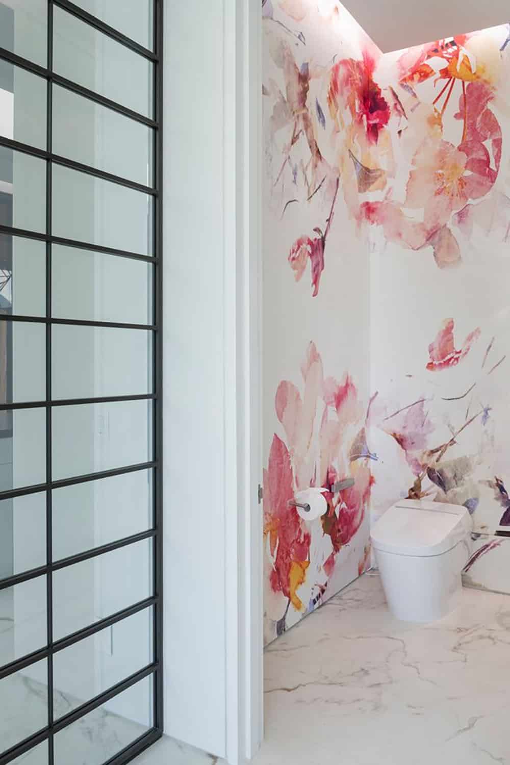 A bathroom with a floral patterned wall and a toilet.