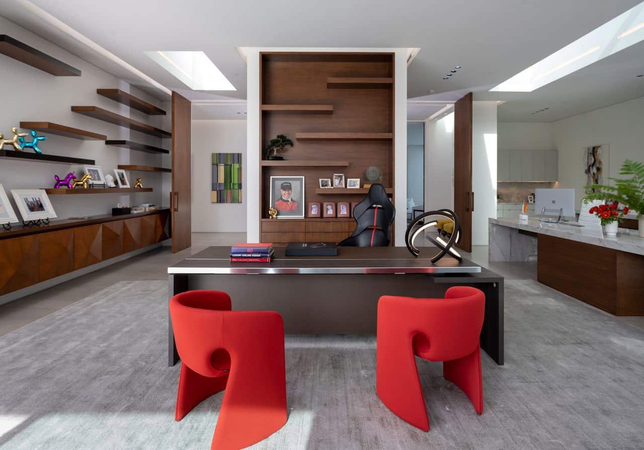 A modern office with red chairs and a desk.