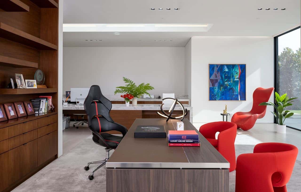 A modern office with red chairs and a desk.