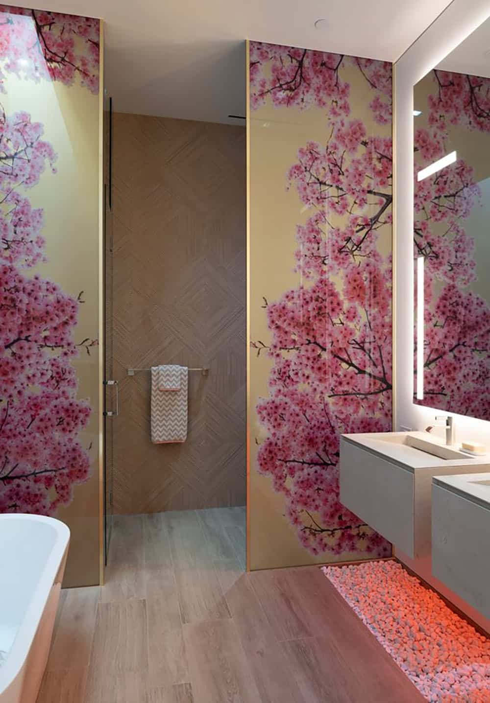 A bathroom with pink flowers on the wall.