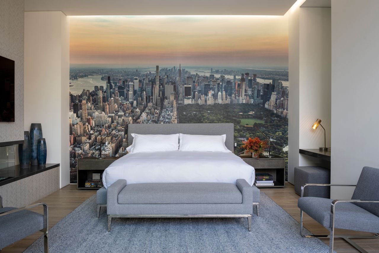 A bedroom with a large wall mural of the city skyline.