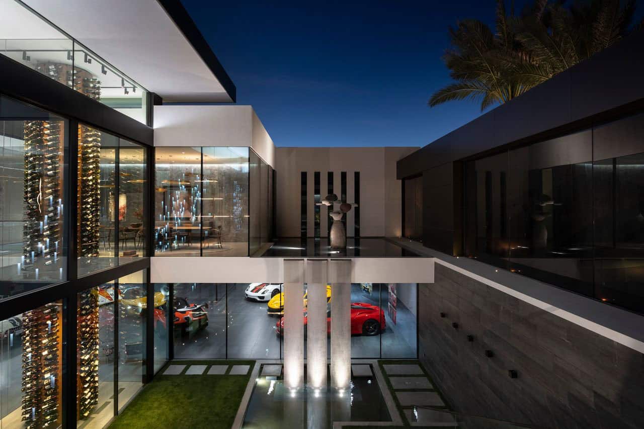 The modern home has a glass wall and a car in the driveway.