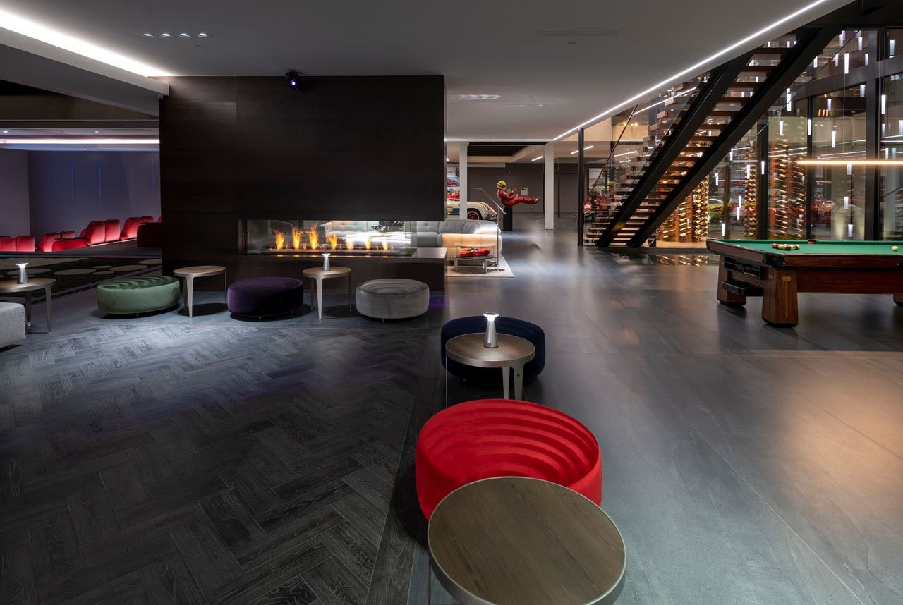 A modern bar with a pool table and red chairs.