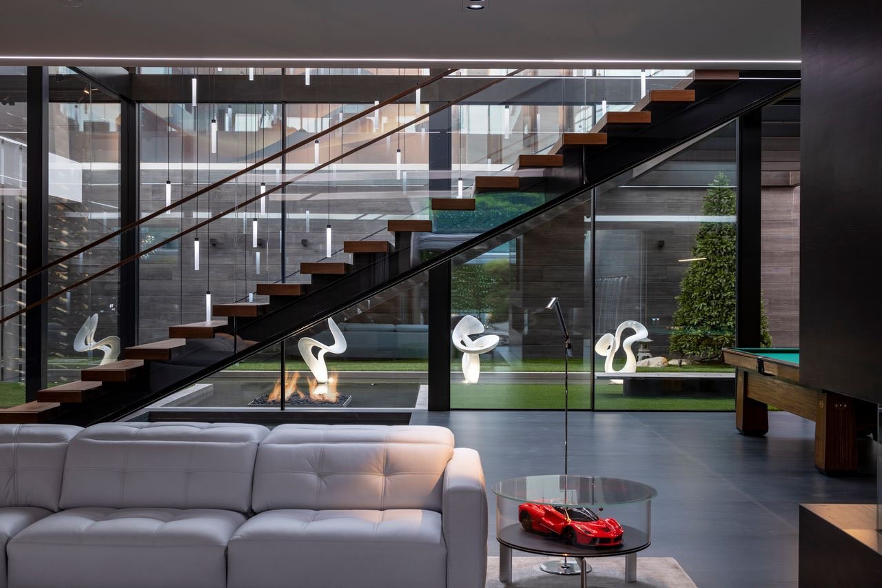 A modern family room with a glass staircase.