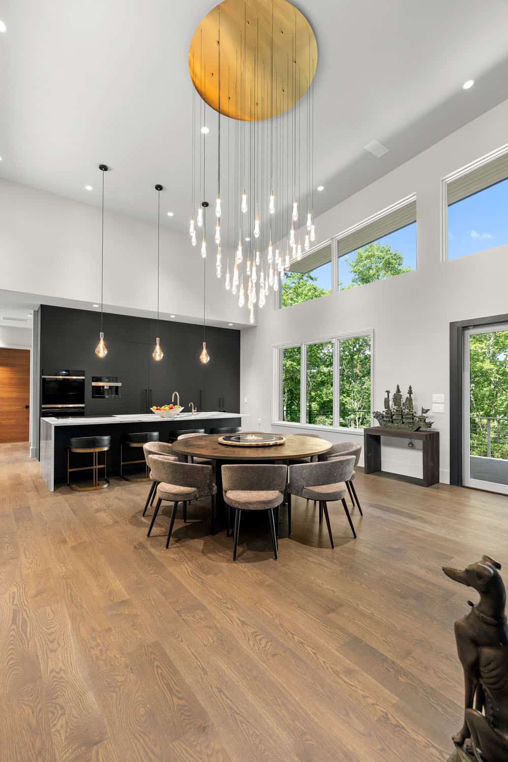 modern dining room and kitchen with two-story ceilings and a large chandelier