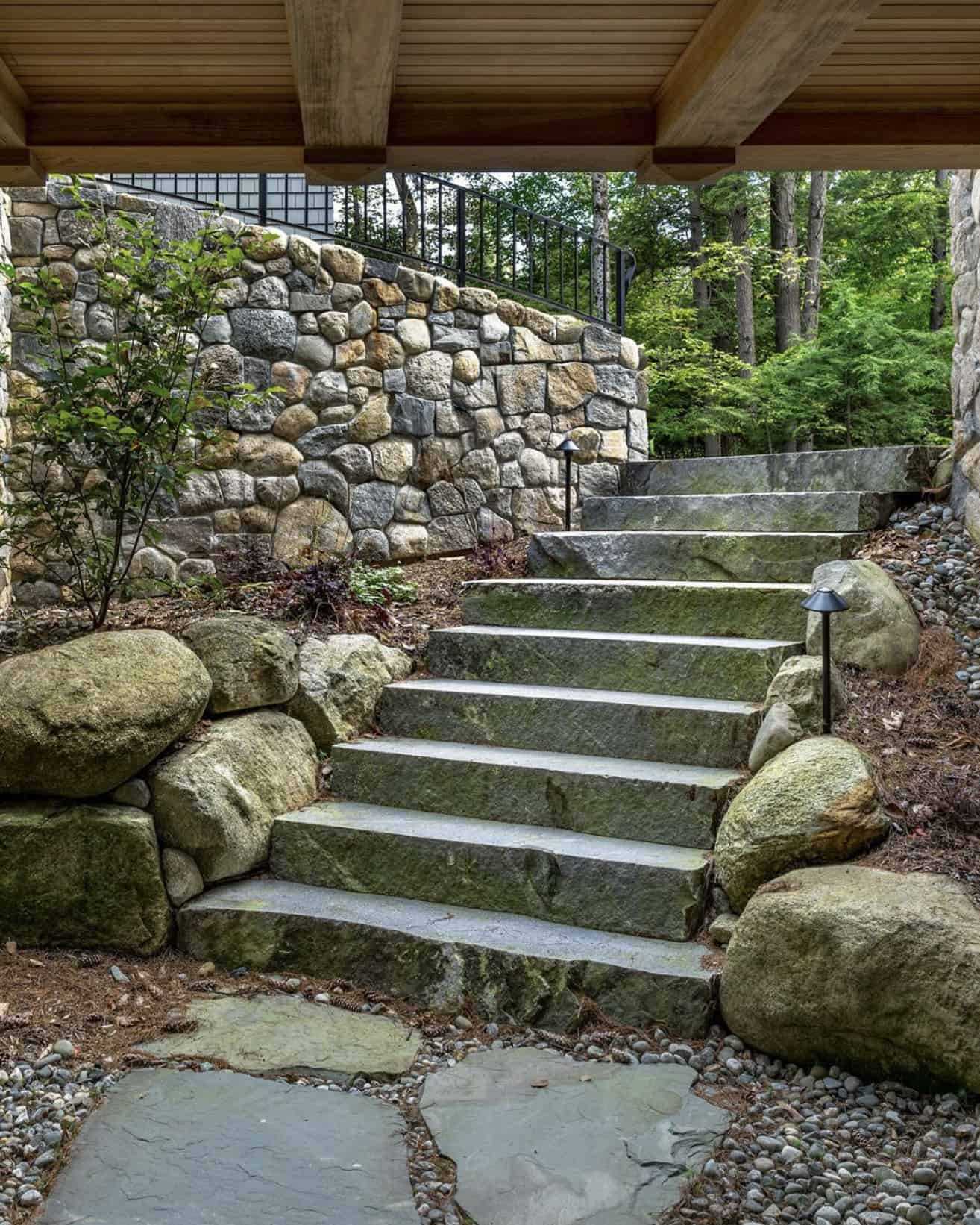new england style lake house exterior stone staircase leading under the glass bridge