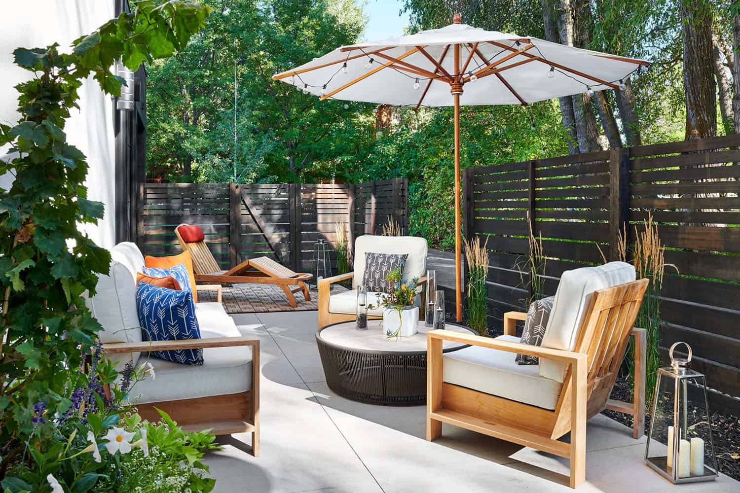 small backyard patio with outdoor furniture, an umbrella and a cedar privacy fence