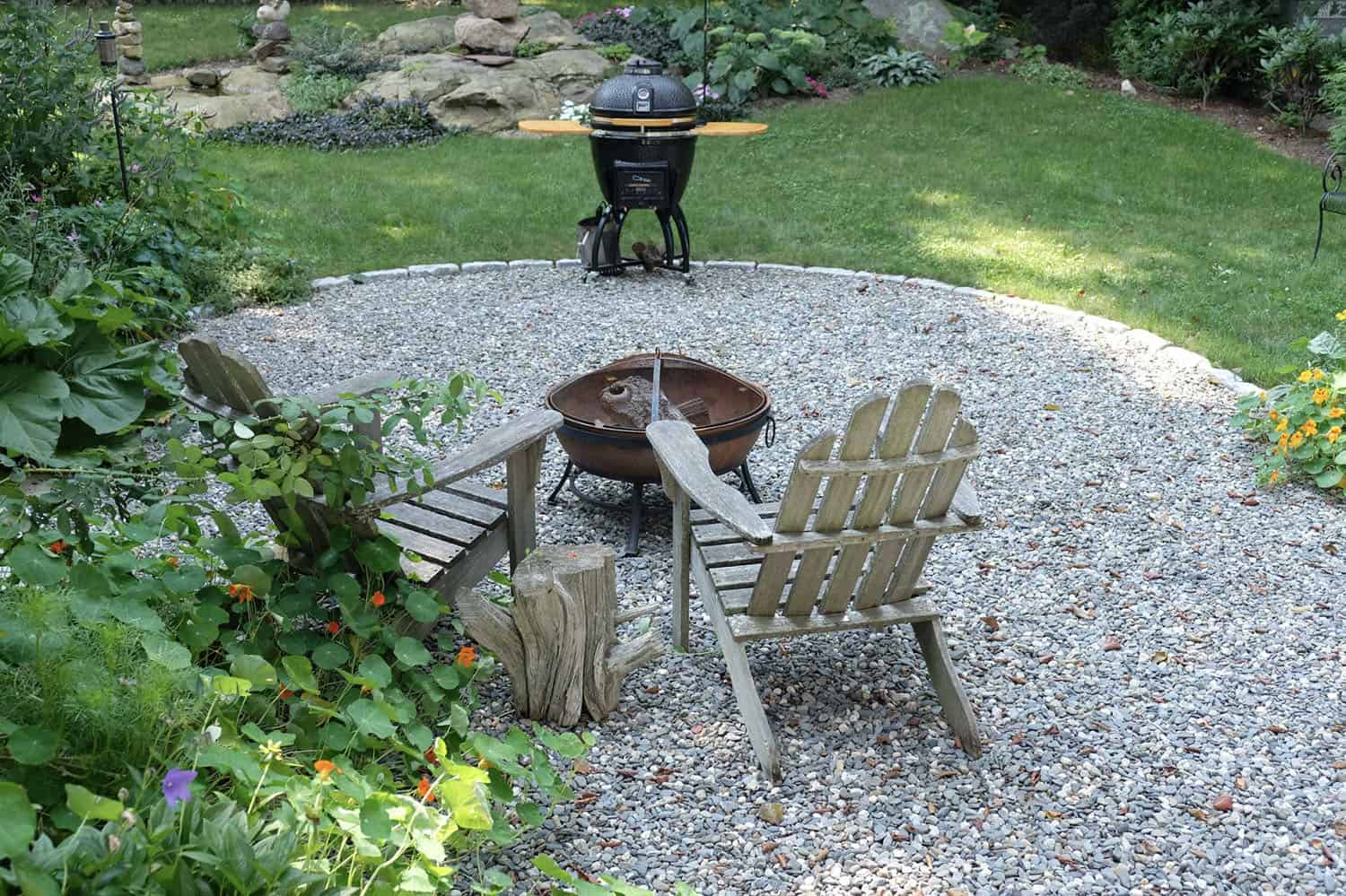 pea gravel backyard patio with adirondack chairs and a fire pit