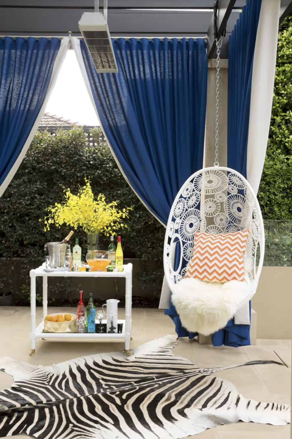 backyard patio with a pergola, hanging chair and a bar cart