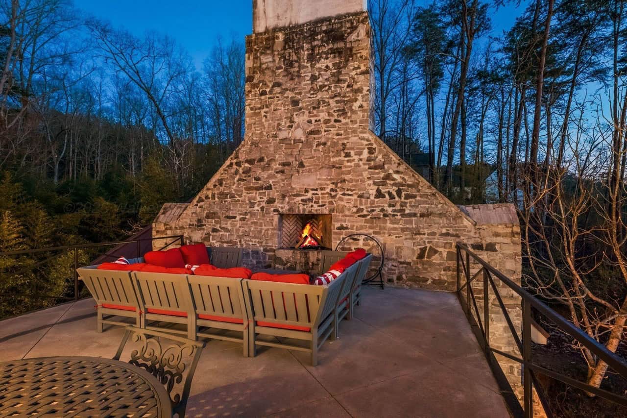 stone lake house exterior with a patio and fireplace