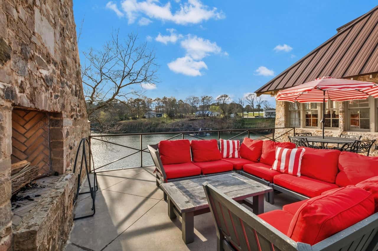 stone lake house exterior with a patio and outdoor furniture