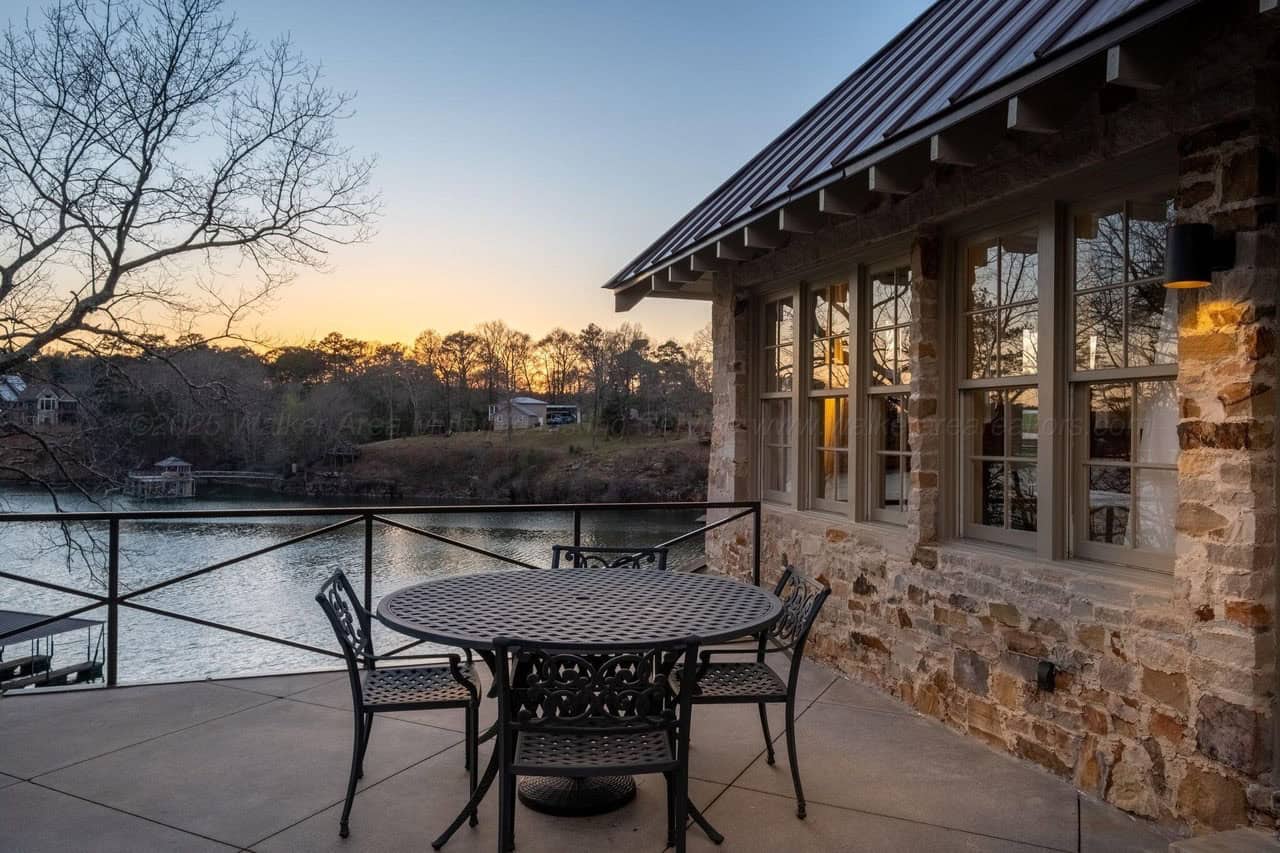 stone lake house exterior with a patio and outdoor furniture