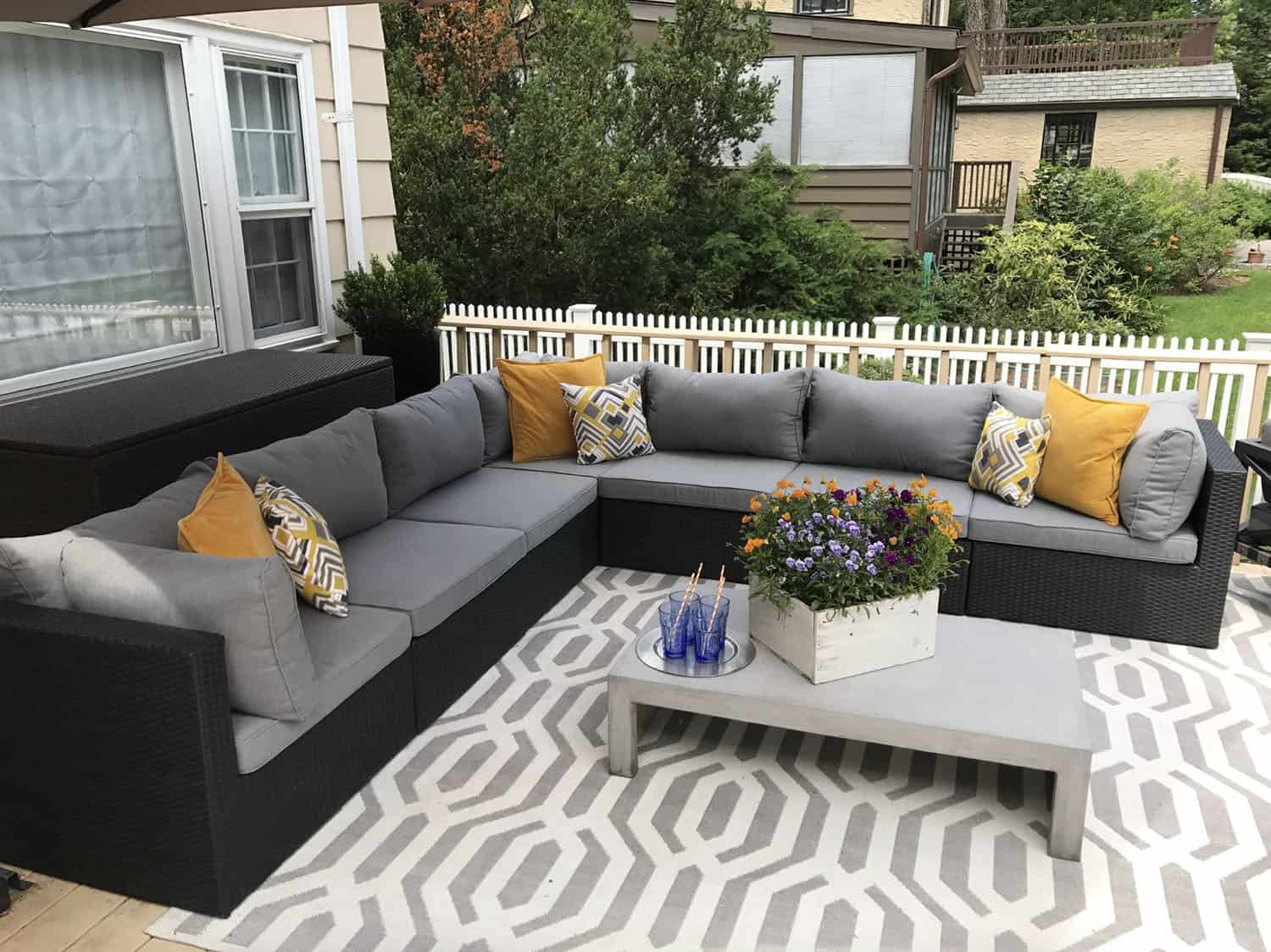 deck with a sectional and coffee table, grounded by an outdoor rug