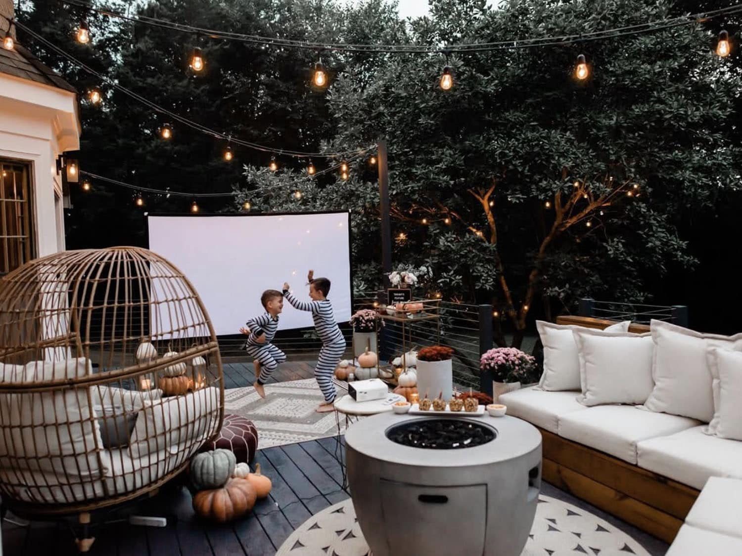 backyard deck with outdoor furniture, a fire pit, movie screen and string lights