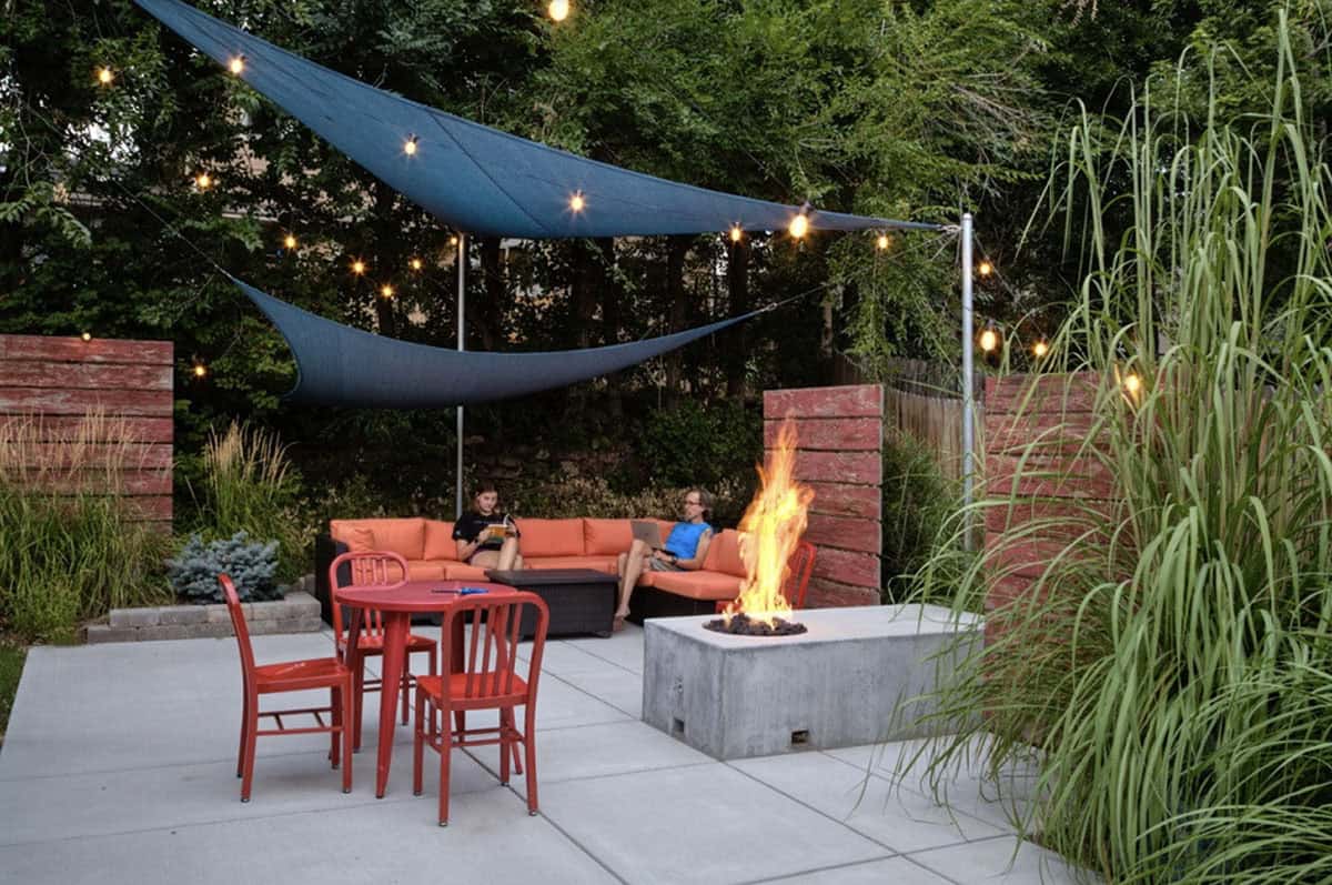 modern patio with a fire pit and sail shades