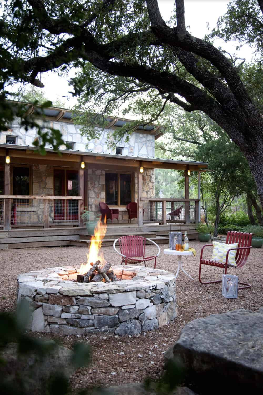 modern farmhouse style home backyard with a fire pit and red chairs
