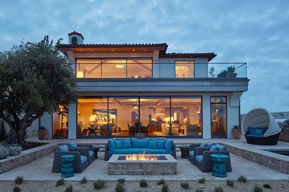 coastal home exterior with a large patio and fire pit at dusk