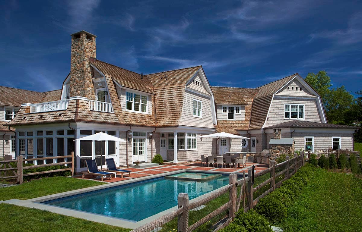 modern country estate exterior with a gambrel roof and a pool
