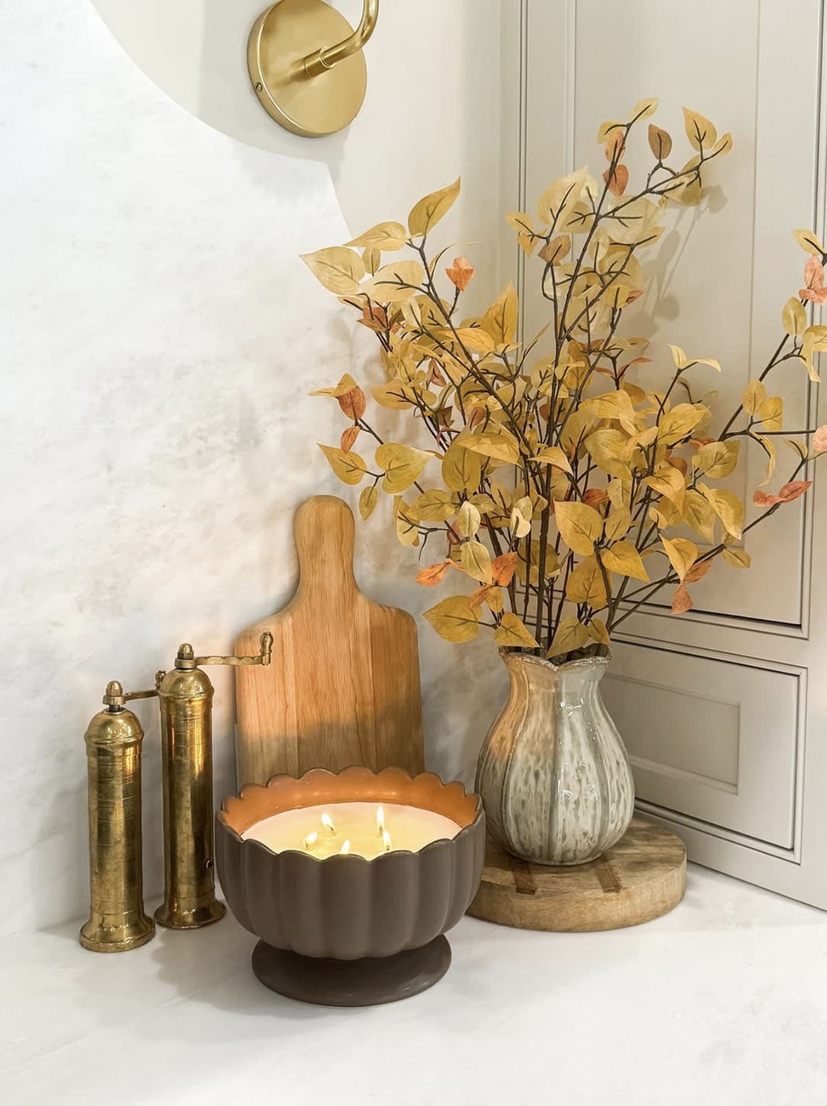 fall decorated vignette with a candle and a vase with faux flowers