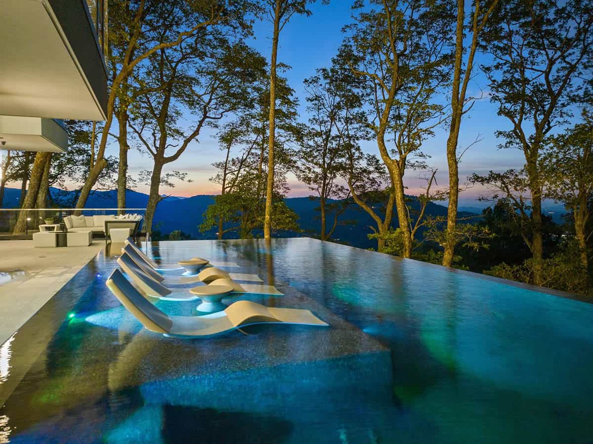 modern mountain home exterior with a pool at dusk