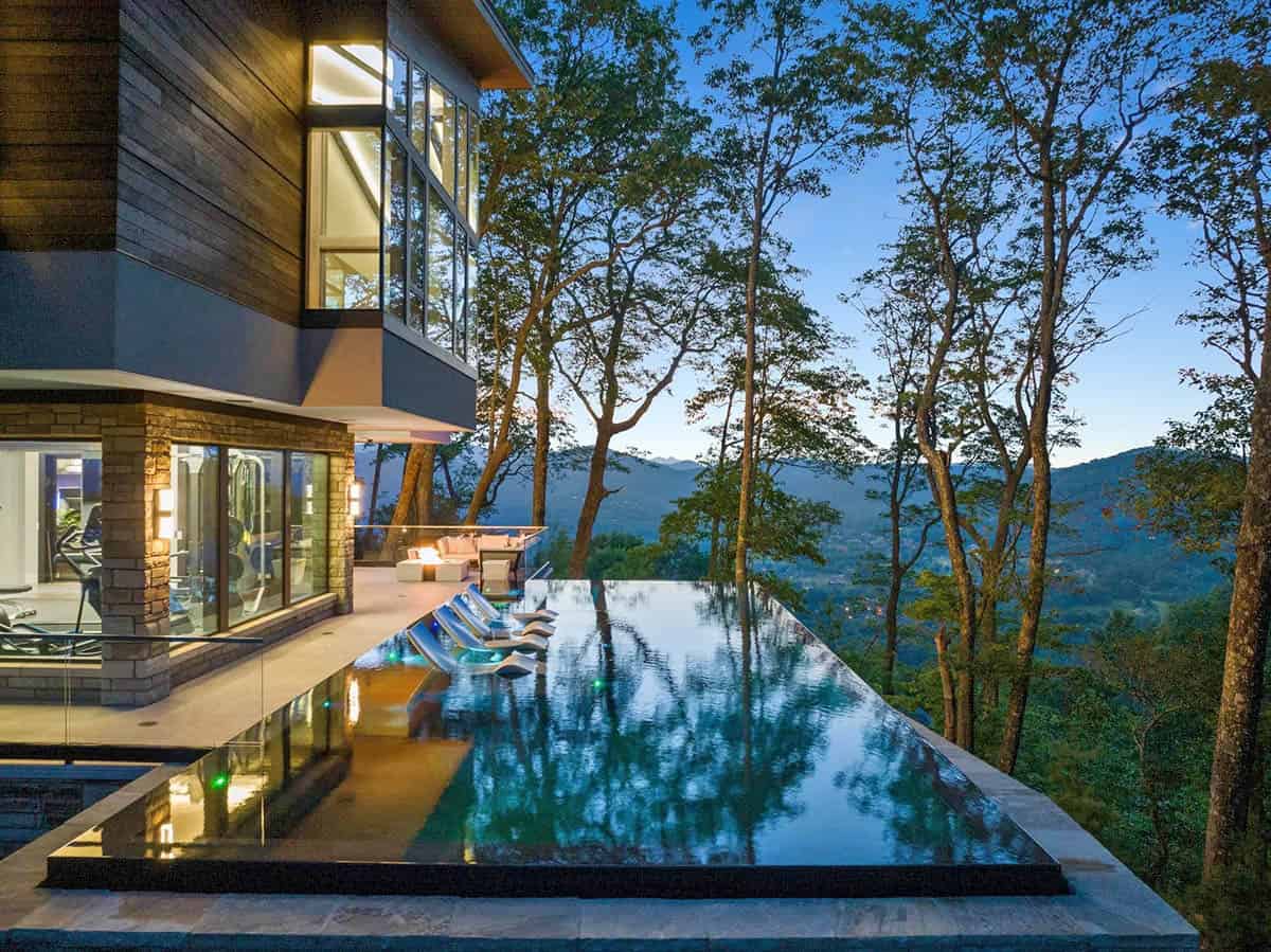 modern mountain home exterior with a pool at dusk