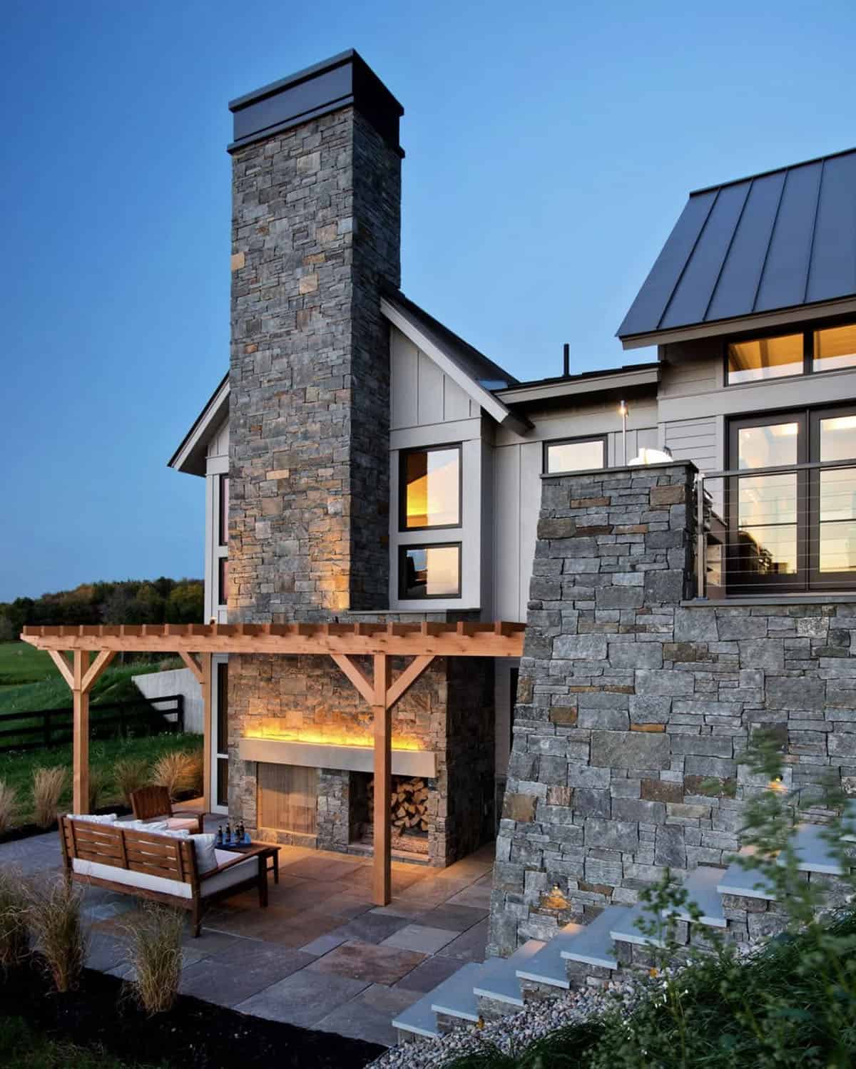 modern farmhouse exterior patio with a fireplace at dusk