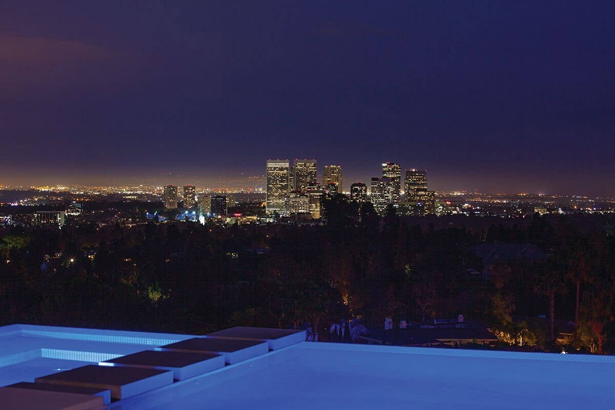 modern home exterior with a pool and skyline views at dusk