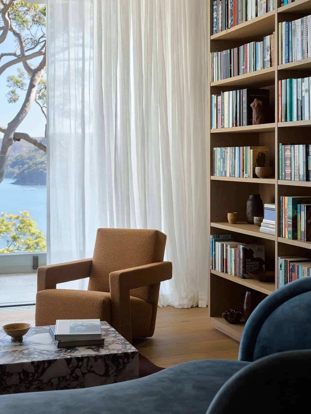 A living room with a large bookcase and a view of the water