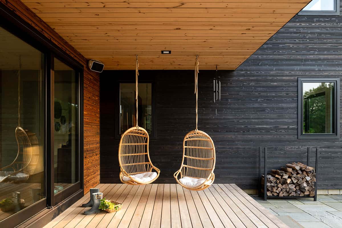 modern home exterior covered porch with hanging chairs