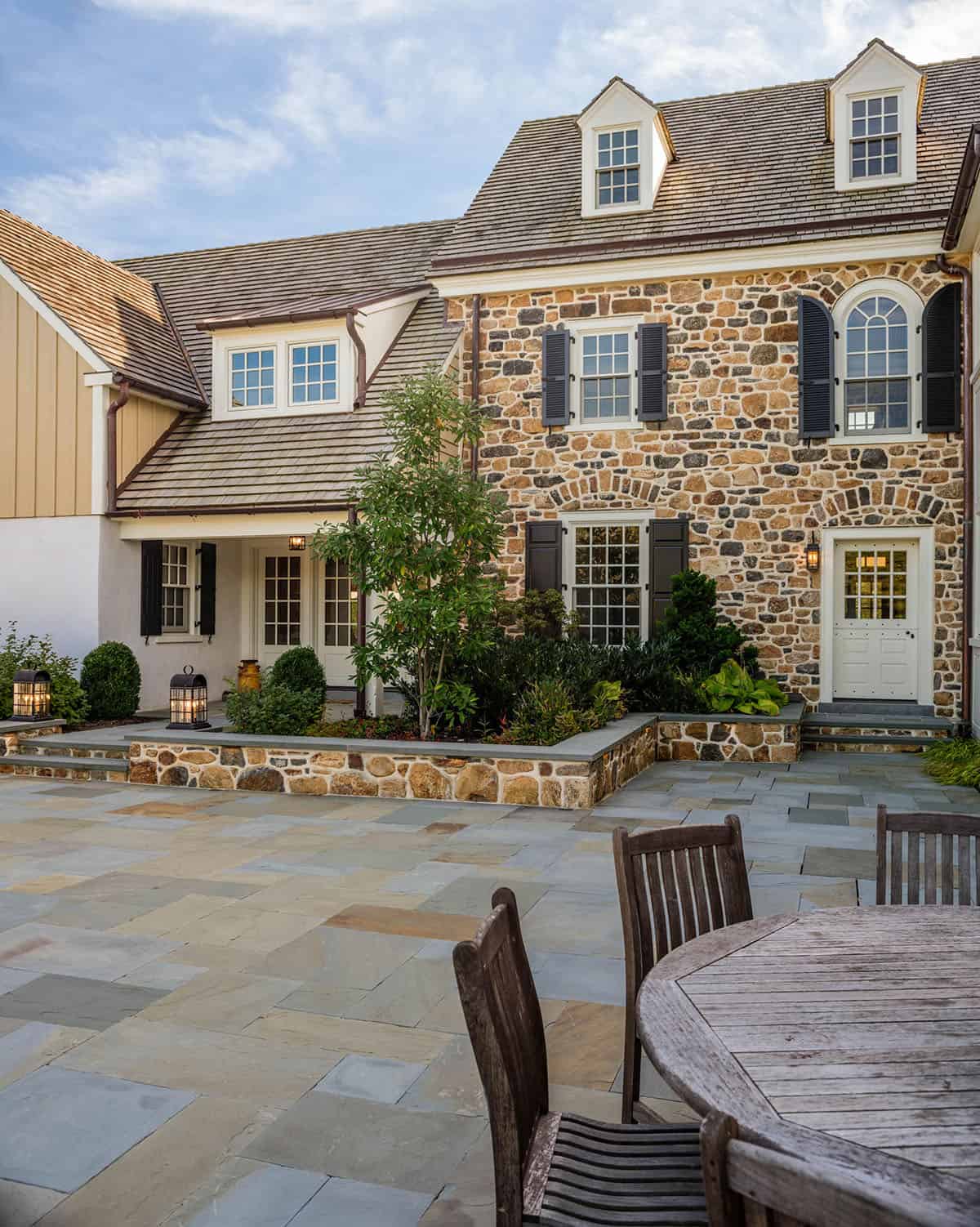 stone farmhouse home exterior backyard patio with outdoor dining