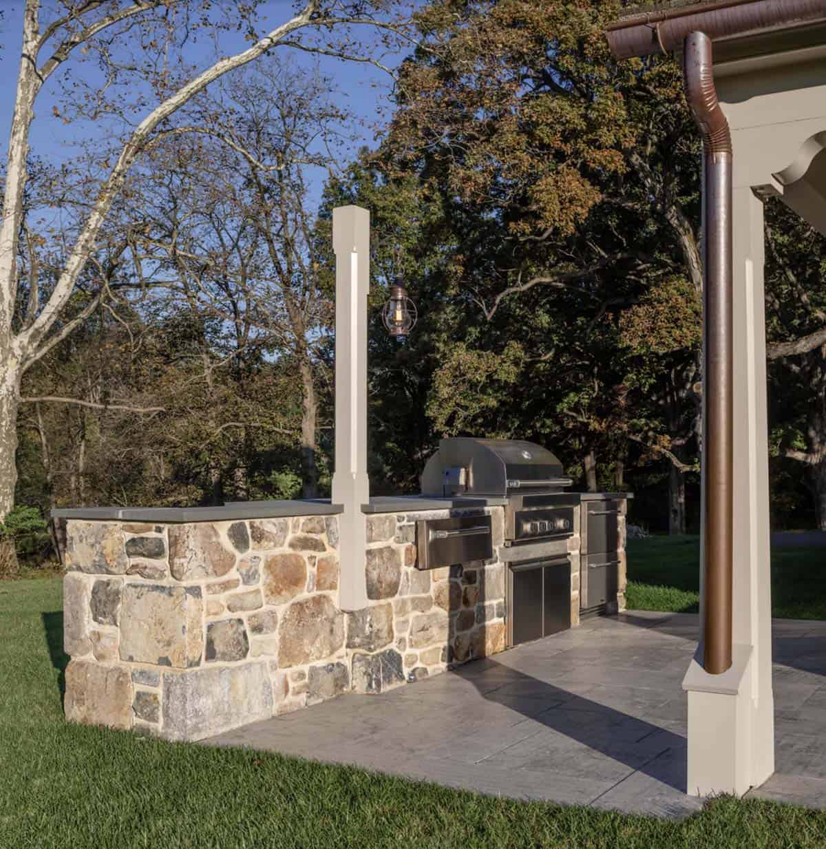 stone farmhouse style house backyard patio with an outdoor kitchen