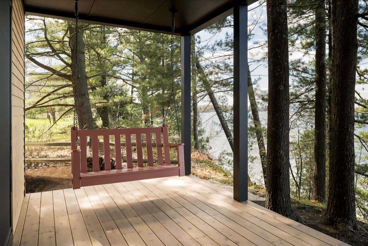 modern lake house exterior covered deck with a hanging swing