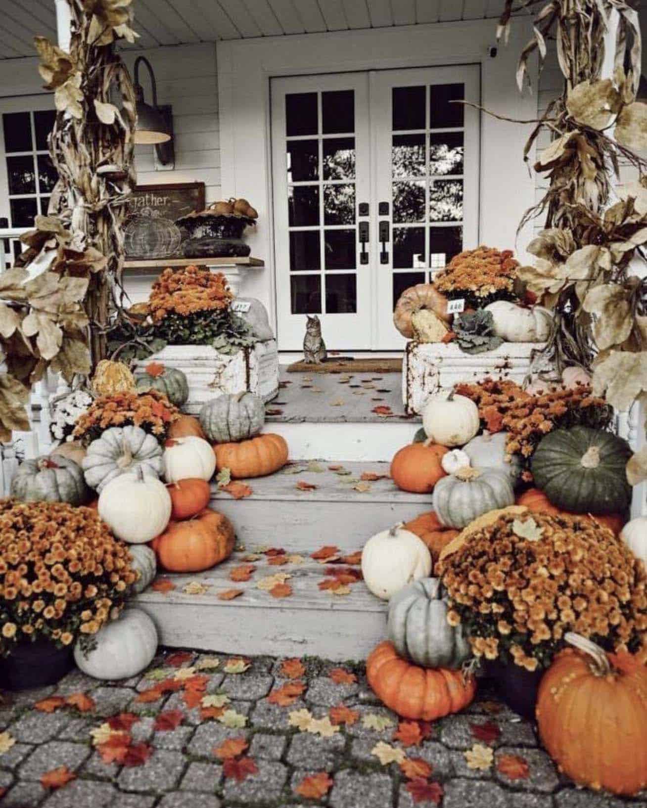front porch decorated for fall with pumpkins and mums