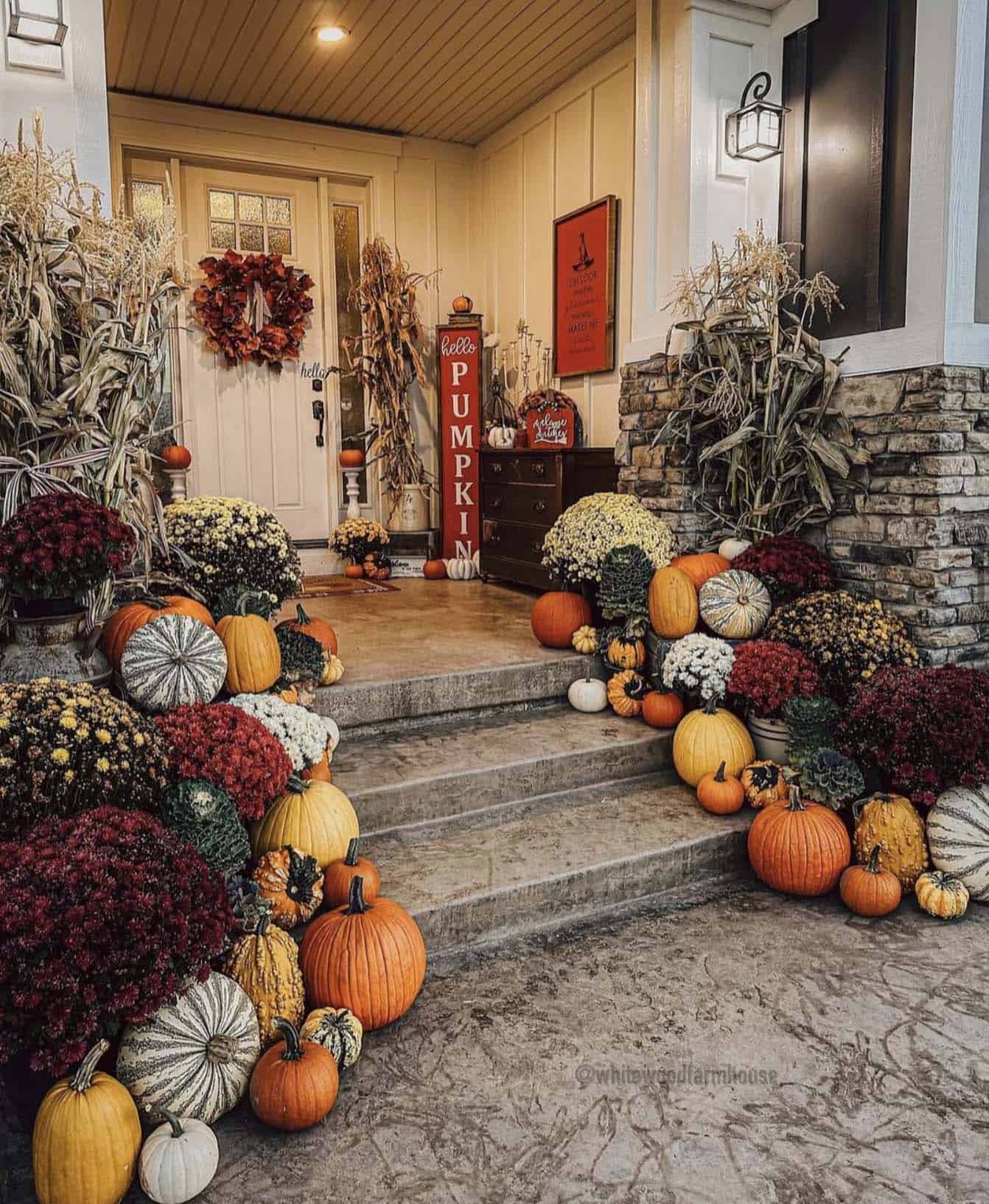 front porch decorated for fall with pumpkins and mums