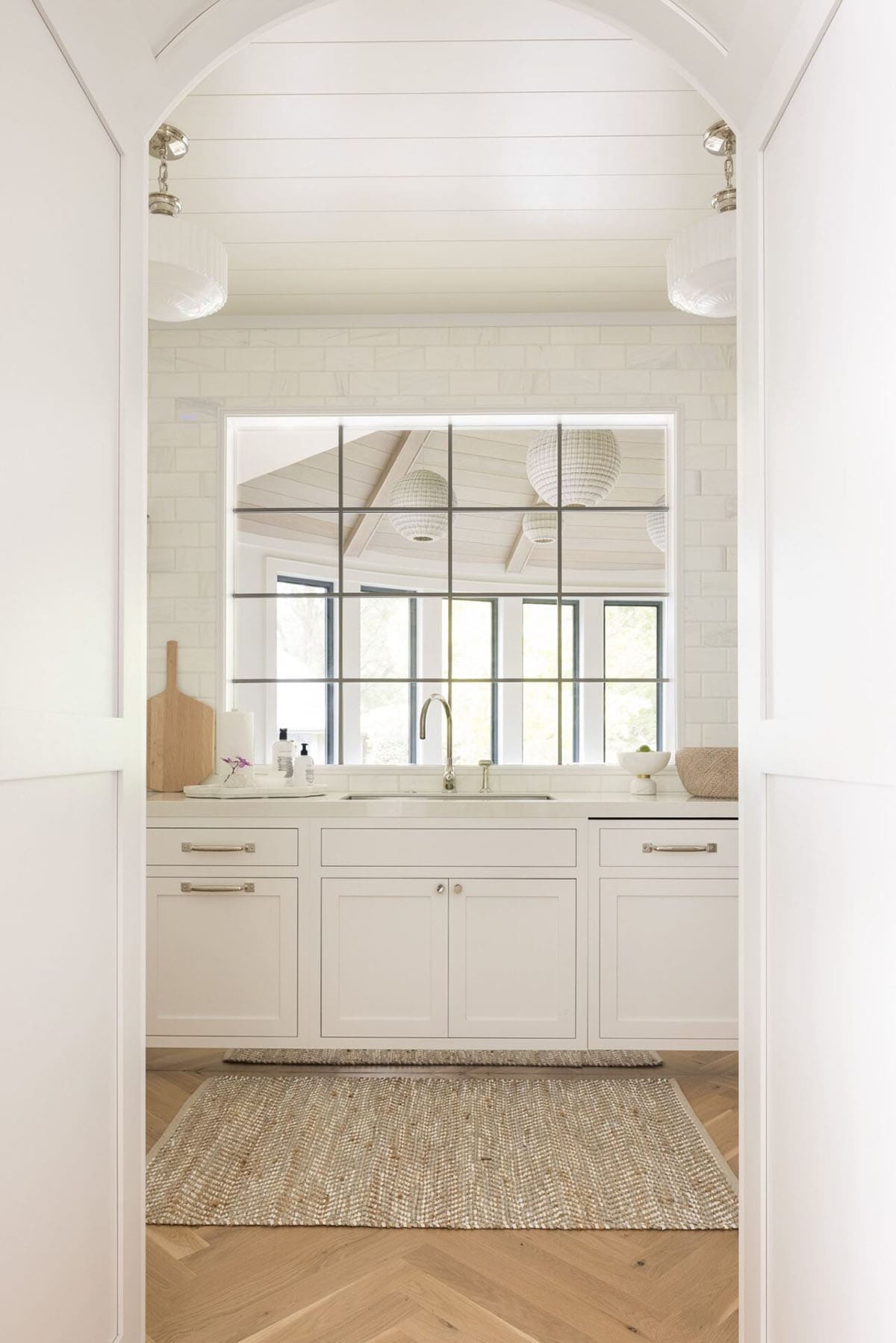Bright white kitchen with large black-framed windows, and white cabinetry
