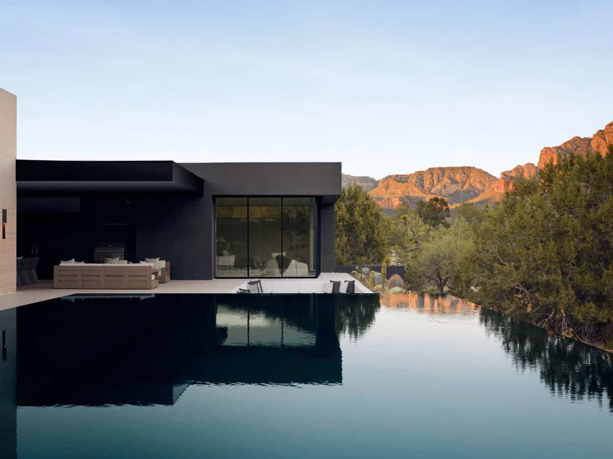 modern mountain home exterior with a pool at dusk