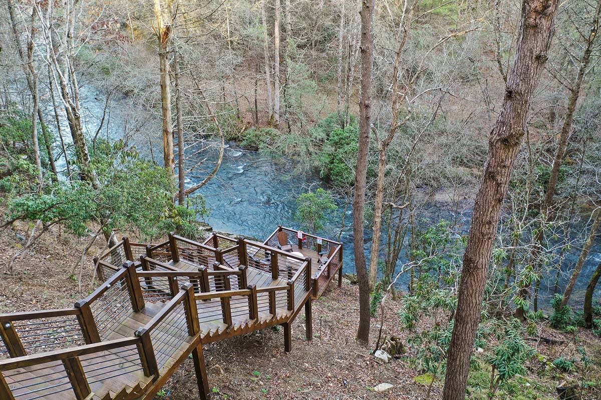 modern rustic log frame cabin exterior with a pathway down to the river