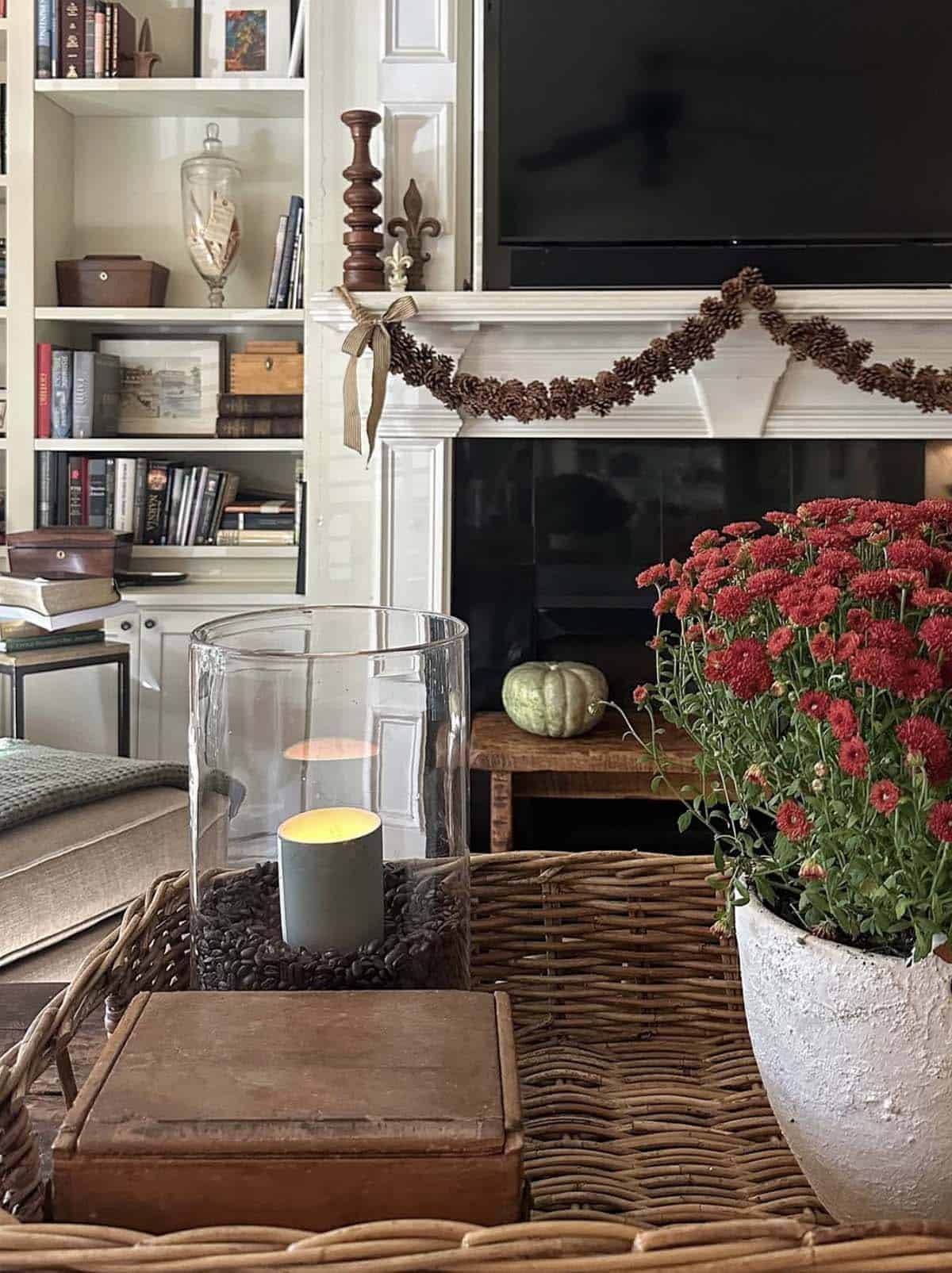 fireplace mantel decorated for fall with a pinecone garland