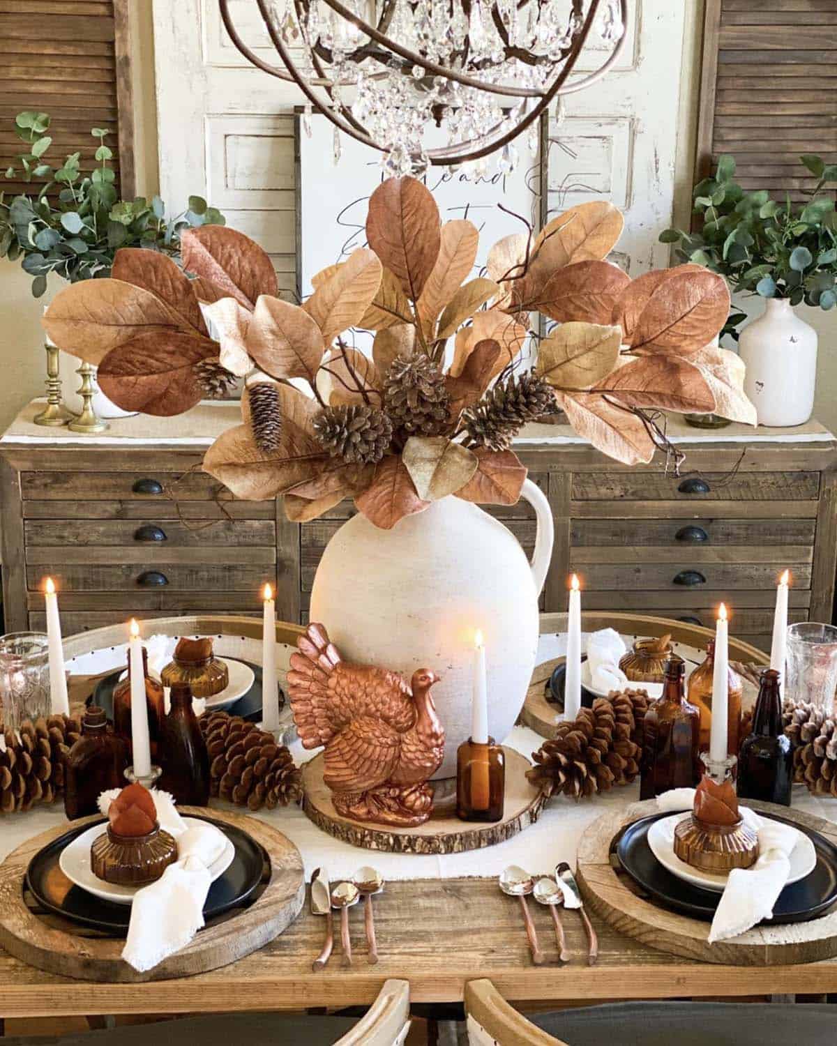 dining table decorated for fall with a large vase filled with flowers and a table runner