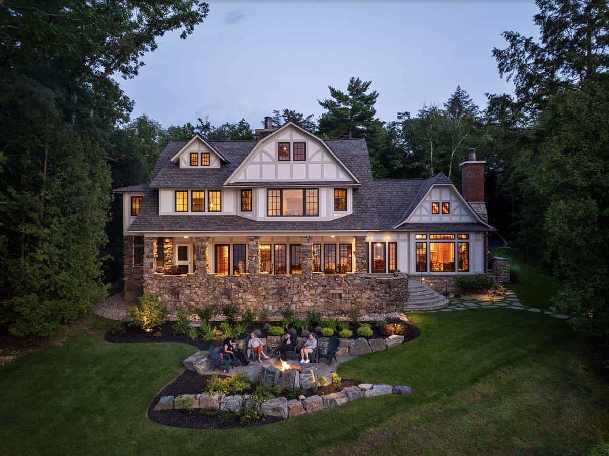 tudor style lake house exterior with a fire pit at dusk