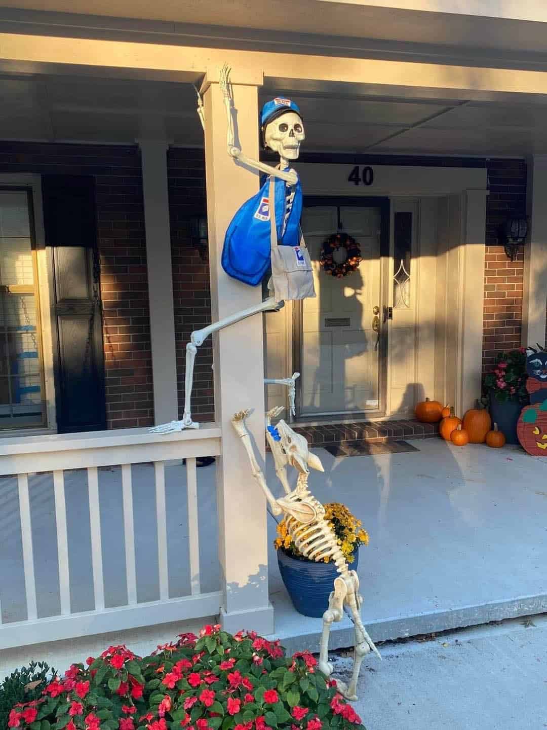 mailman skeleton chased up the front porch railing by a dog skeleton